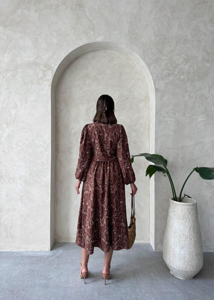 Back view of a woman in a Boho printed linen two-piece set, standing in a minimalist space with potted plant and archway.