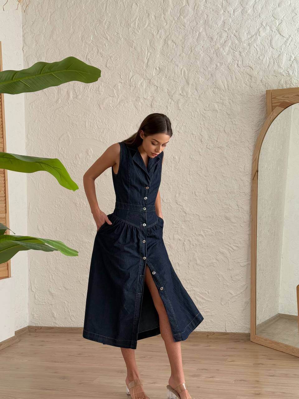 Model wearing a sleeveless navy blue denim midi dress with a button-down A-line design.