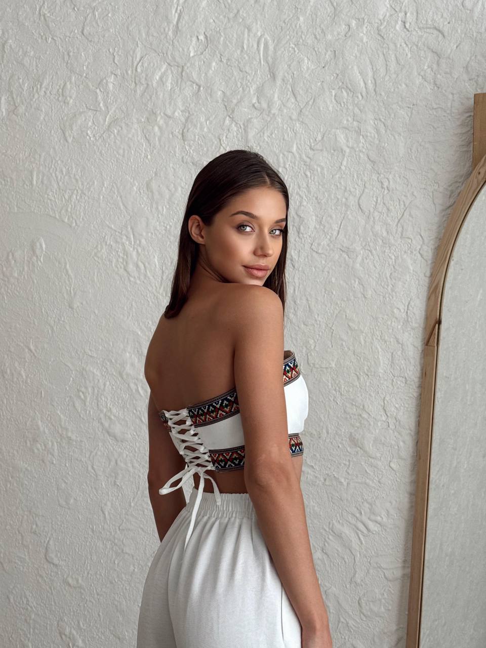 Back view of a woman modeling a white bohemian two-piece set, showing the flowy wide-leg pants.