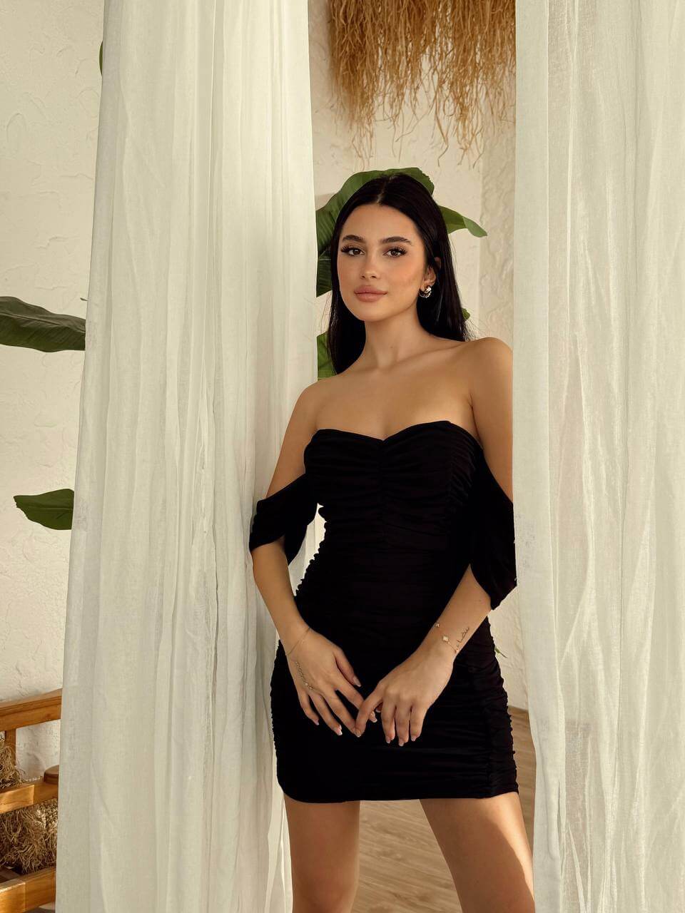 Black Off-Close-up of a black off-shoulder ruched mini dress, showing the texture of the fabric and the details of the ruching.Shoulder Ruched Mini Dress