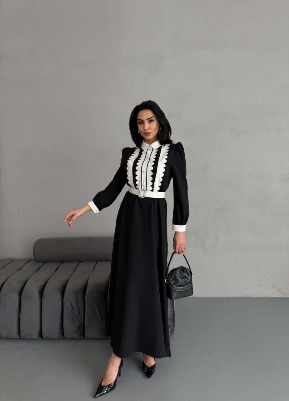  full-length view of a black and white women's maxi dress, showcasing the A-line silhouette and button-up details.
