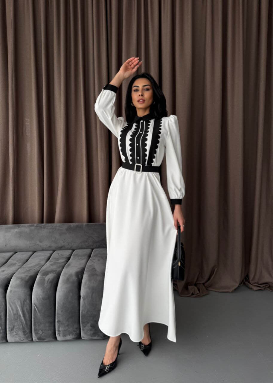 A full-length shot of a white and black women's maxi dress, featuring a classic design with contrasting details.
