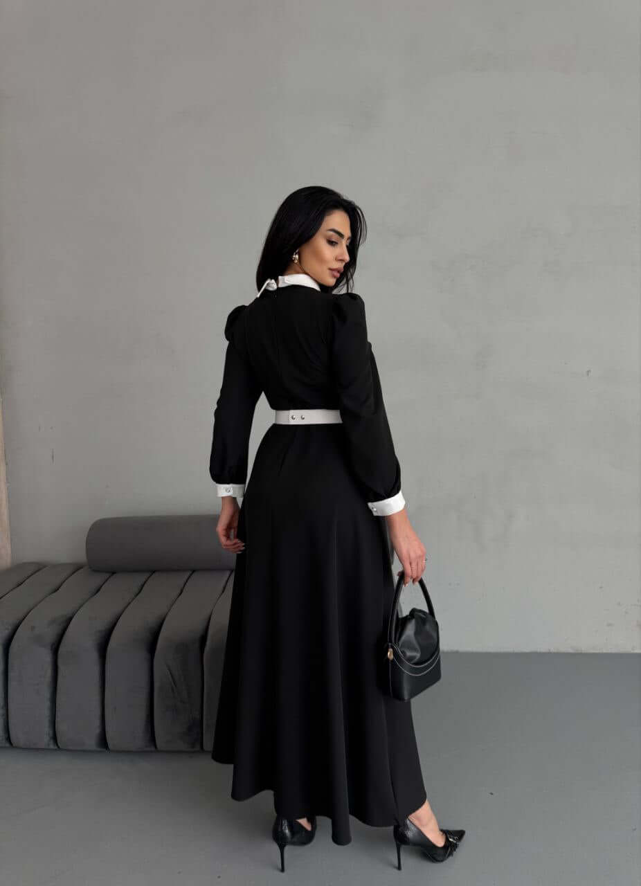 The back view of a black and white maxi dress, highlighting the elegant design and fabric flow.
