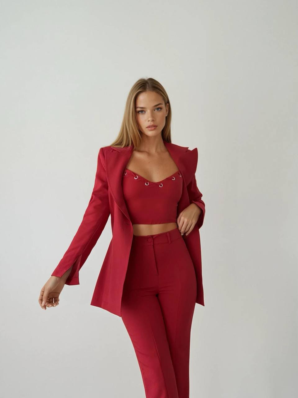 Close-up shot of the model's upper body wearing the red set including a blazer, crop top, and slit pants.