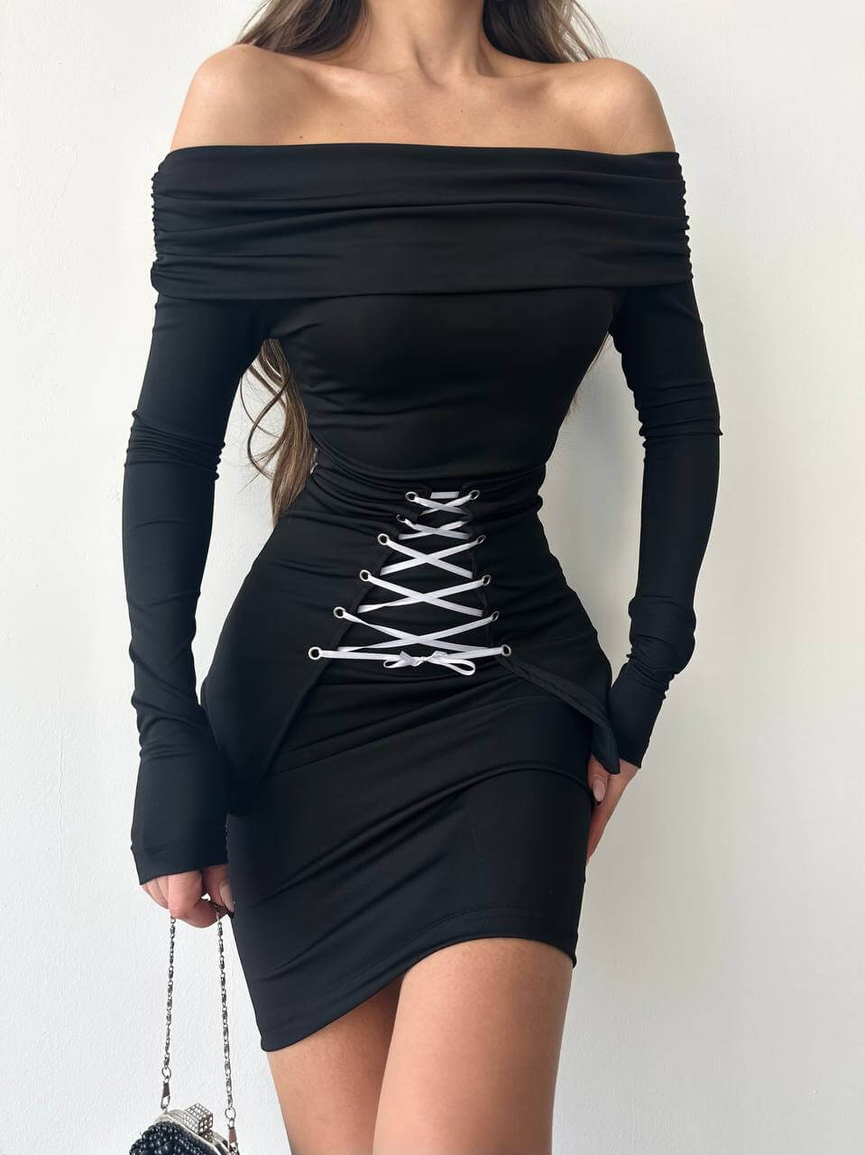 Close-up of the black off-shoulder bodycon mini dress, emphasizing the lace-up corset and fabric texture.