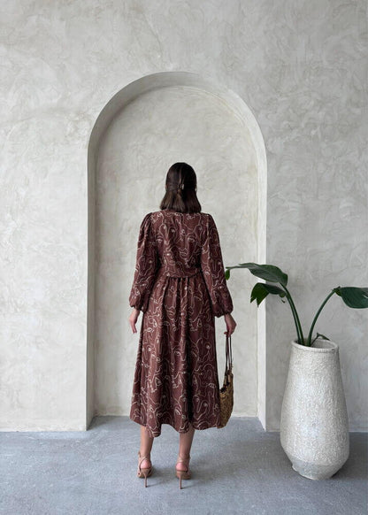 Back view of a woman in a Boho printed linen two-piece set, standing in a minimalist space with potted plant and archway.