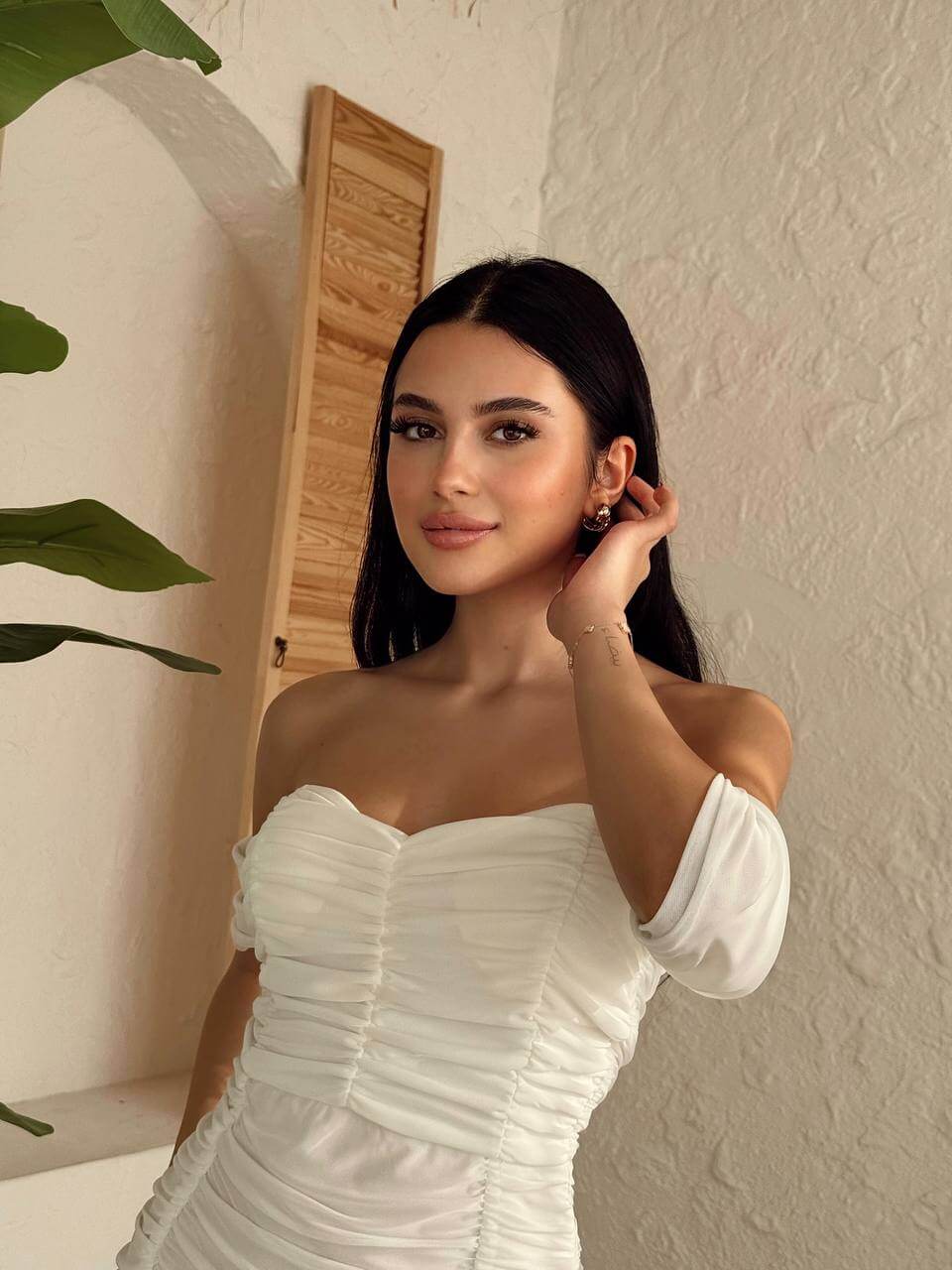 Detailed view of the off-shoulder neckline and delicate ruching on a white mini dress.