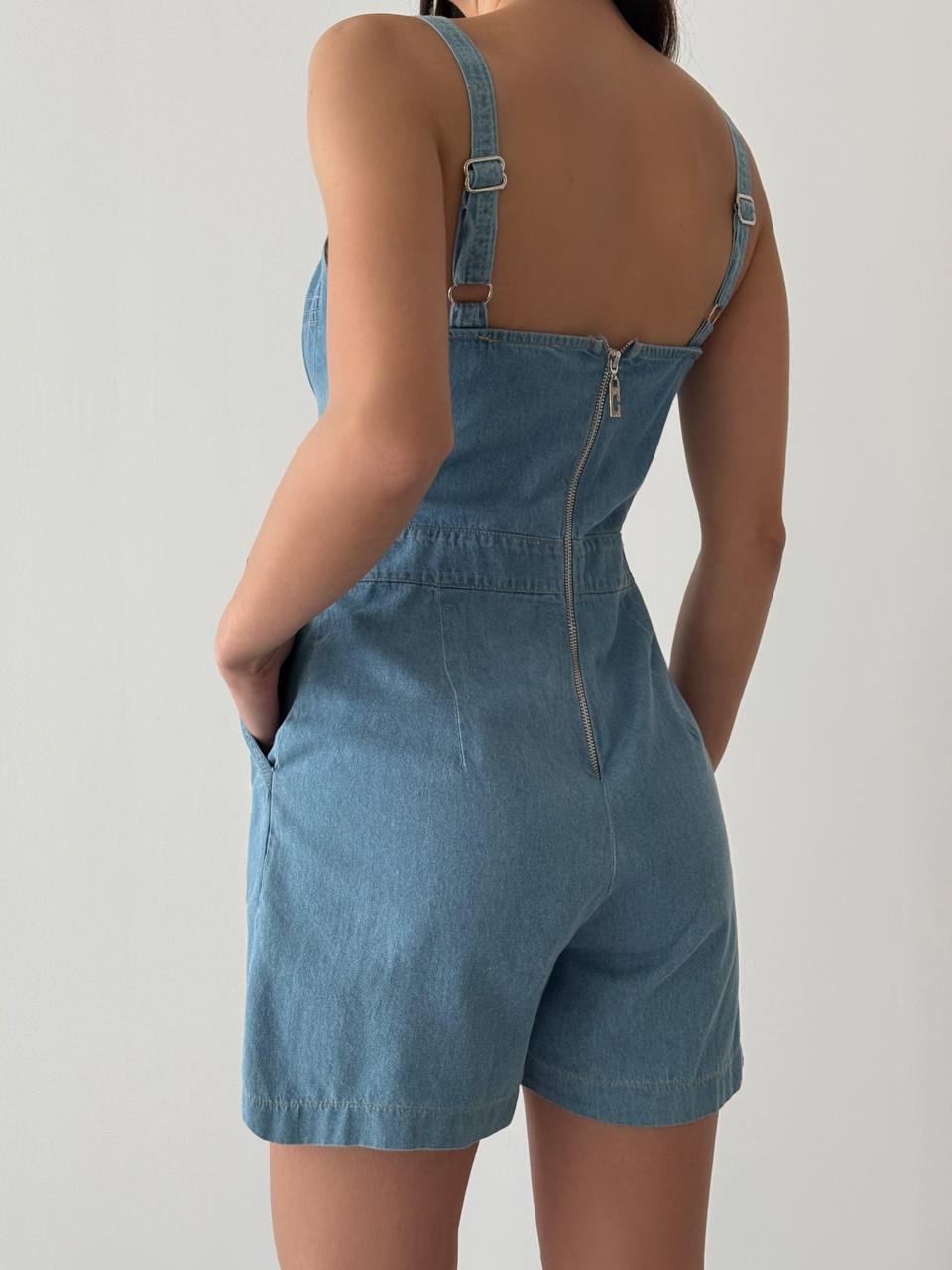 Light blue denim strap romper, back view