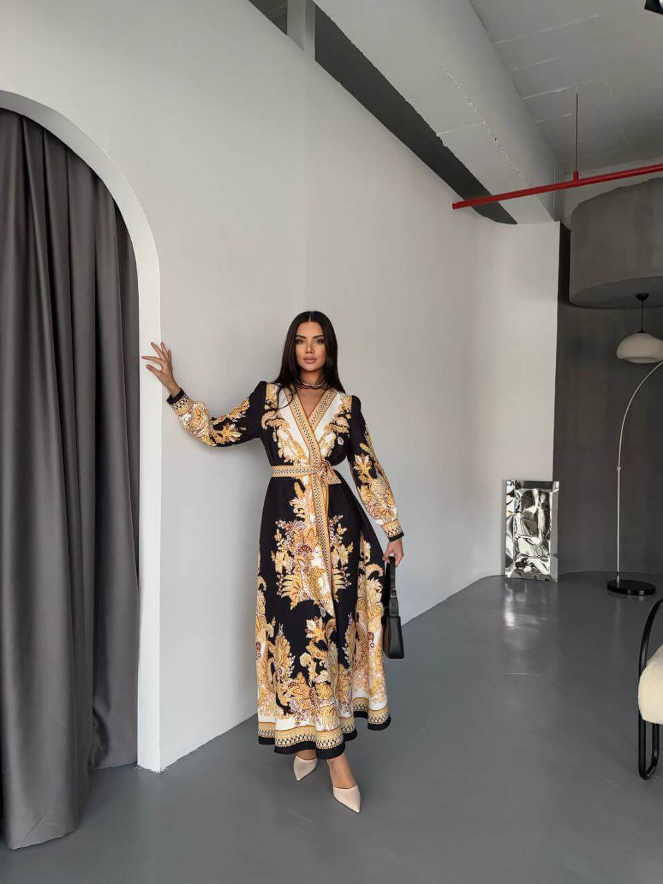 A woman wearing a long, elegant dress poses for the camera.
