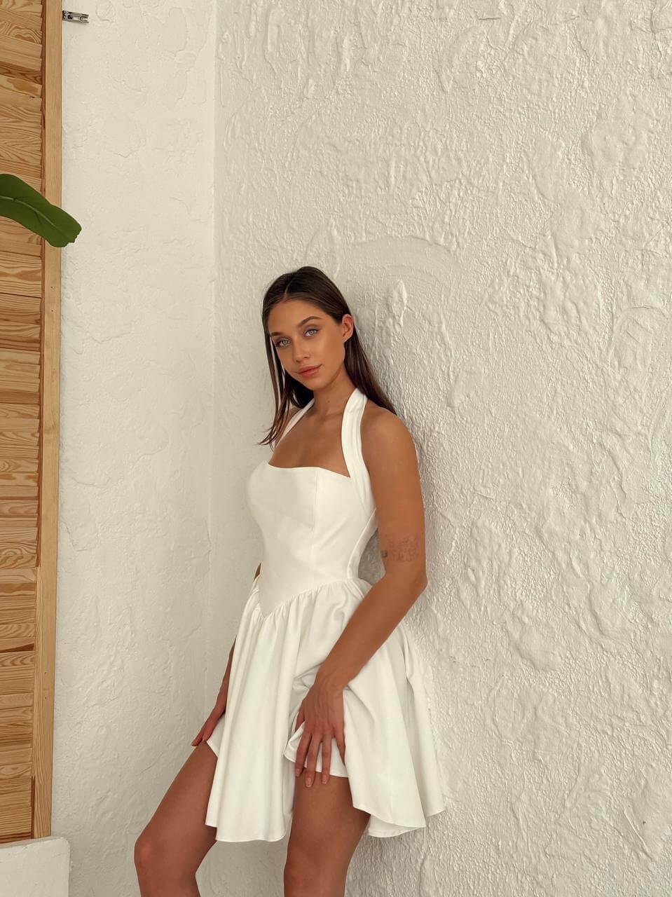 Short white-colored dress with a halter neckline, open back, and flared skirt.