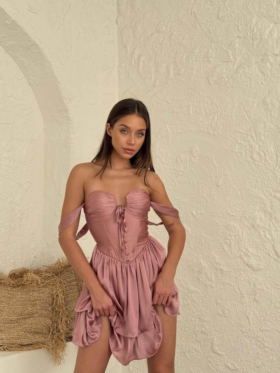 Pink sleeveless short dress with pin-pleated skirt above the knee.