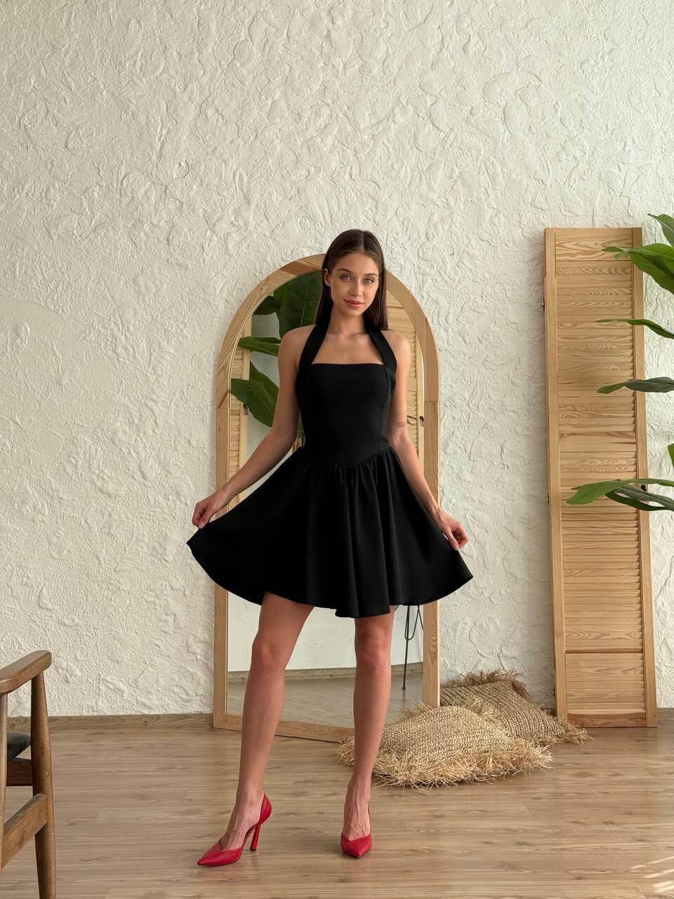 Short black-colored dress with a halter neckline, open back, and flared skirt.