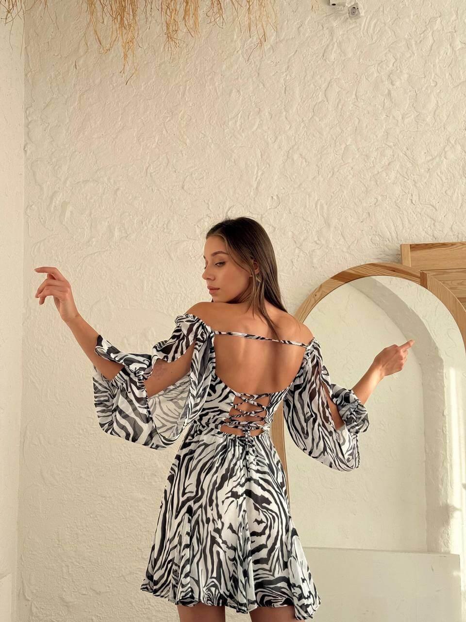Women's short zebra-print dress with an open back, deep front neckline, long slit sleeves.