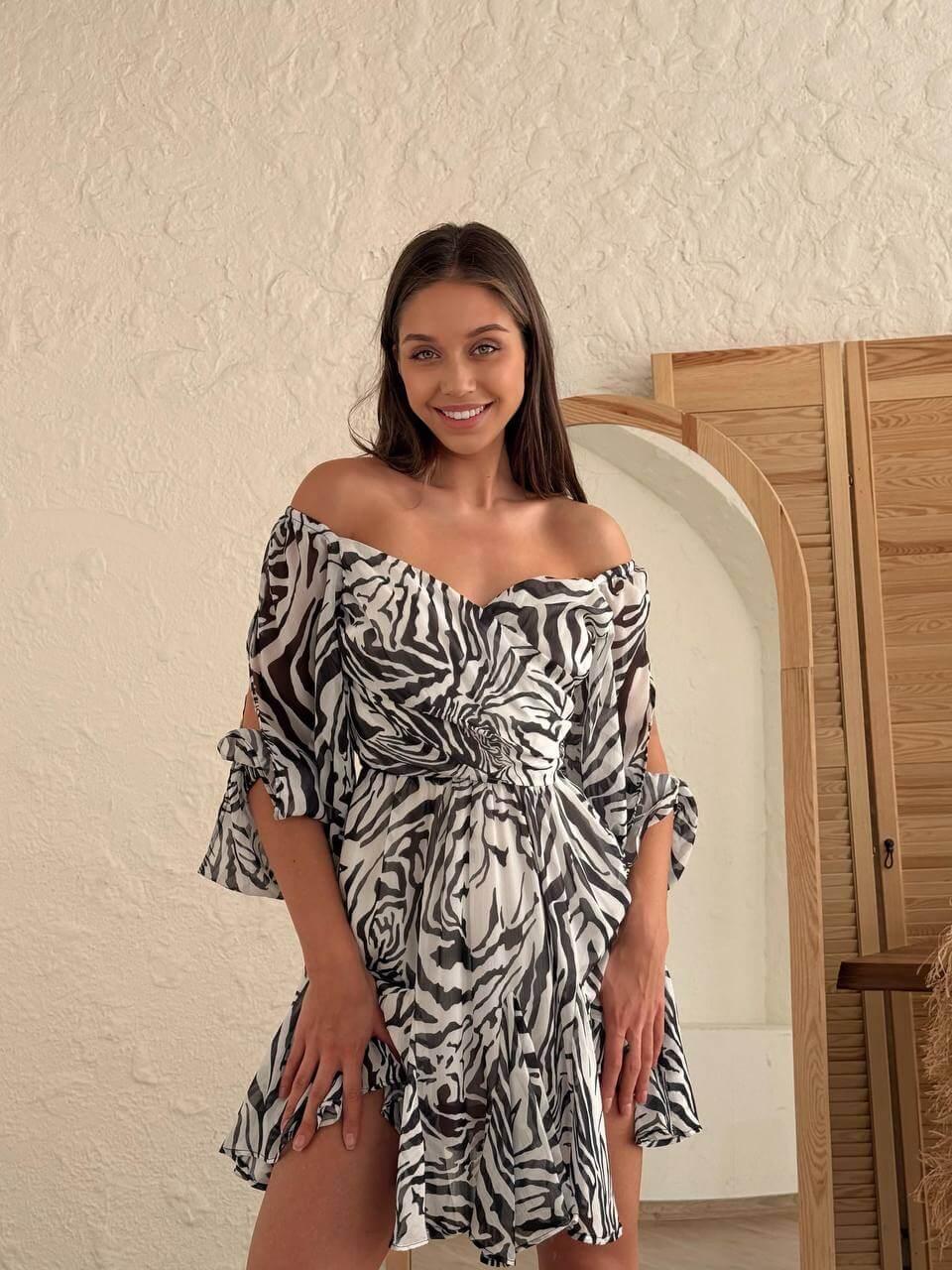 Women's short zebra-print dress with an open back, deep front neckline, long slit sleeves.