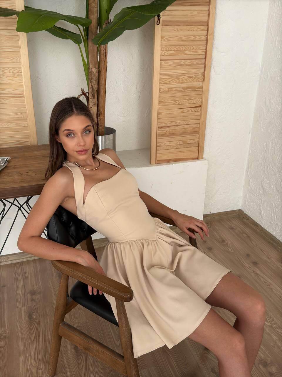 Short cream-colored dress with a halter neckline, open back, and flared skirt.