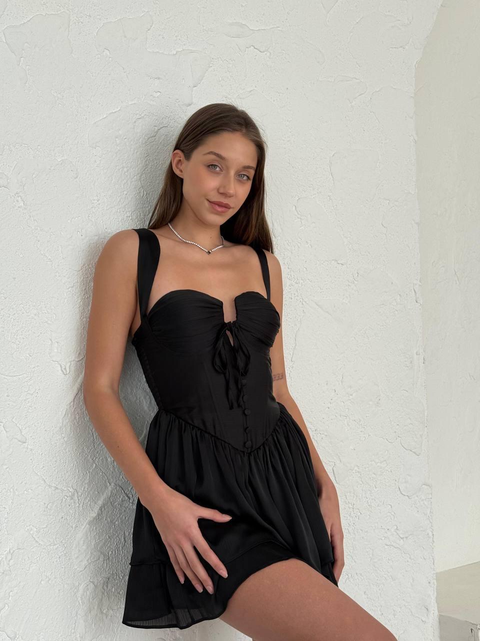 Black sleeveless short dress with pin-pleated skirt above the knee.