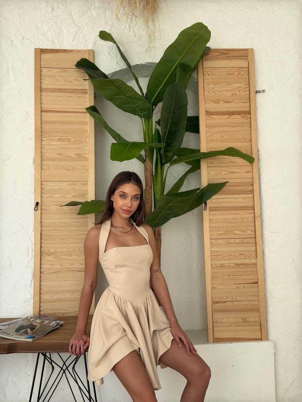 Short cream-colored dress with a halter neckline, open back, and flared skirt.