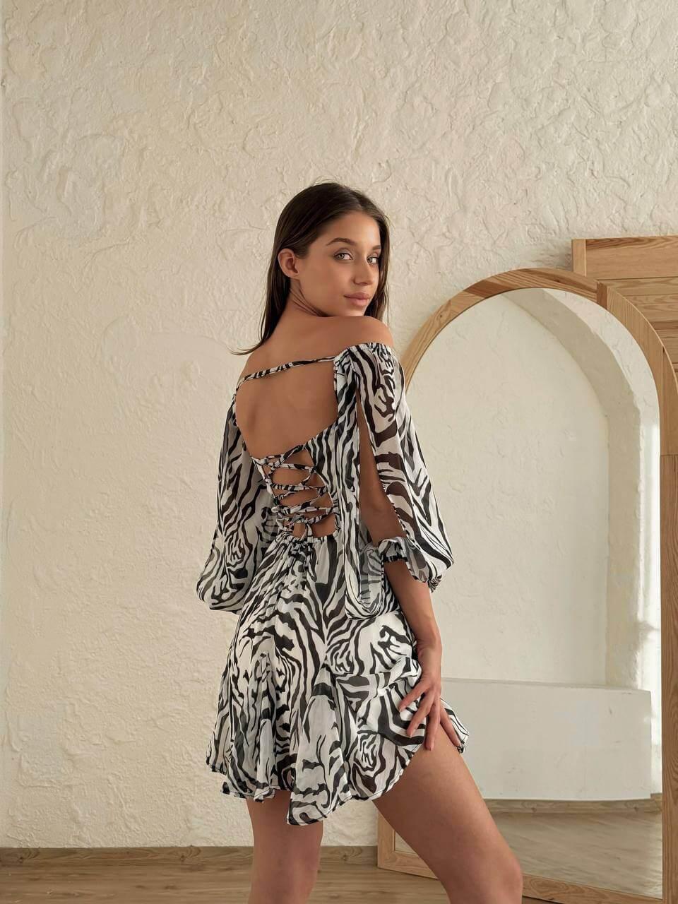 Women's short zebra-print dress with an open back, deep front neckline, long slit sleeves.